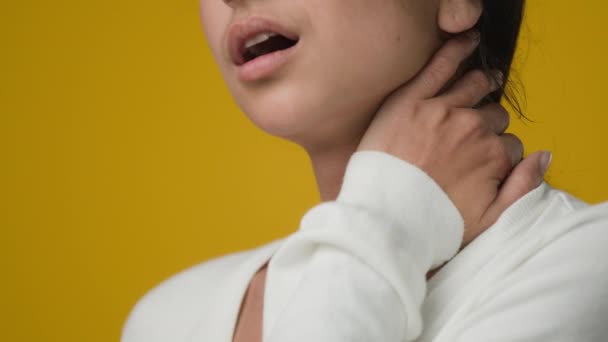 Close up studio yellow background Indian sad ethnic woman girl lady female suffer pain ache in neck rubbing muscle tension cervical osteochondral problem tired bad posture trouble sick trauma damage - Footage, Video