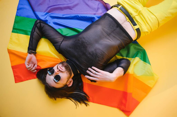 Веселый гей с радужным флагом в руках символ ЛГБТК-сообщества. - Фото, изображение