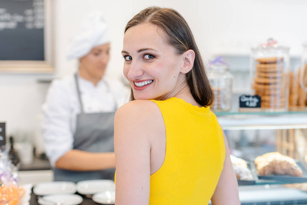 Жінка в кондитерському магазині вибирає солодкі десерти з очікуванням
 - Фото, зображення