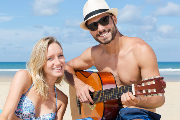 couple on the beach man playing guitar - 写真・画像
