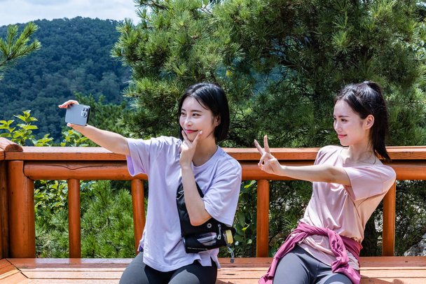 korean young women hiking and plogging, taking a selfie - 写真・画像