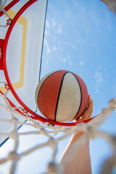 μπασκετμπολίστας ρίχνει την μπάλα στο στεφάνι, κοντινό πλάνο, αθλητική επιτυχία. - Φωτογραφία, εικόνα