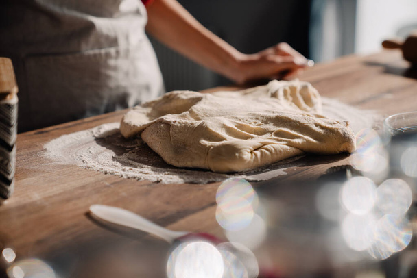 Young woman wearing apron cooking and kneading dough in kitchen at home - Fotoğraf, Görsel