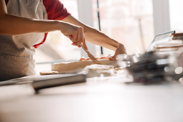 Young hispanic woman wearing apron making pie in kitchen at home - Foto, Bild