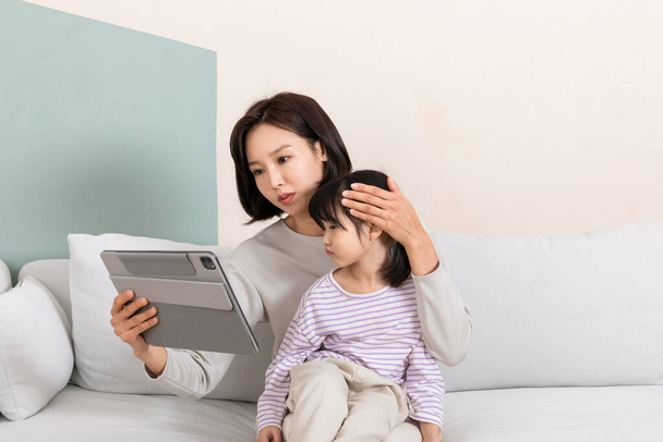 Korean child and mom using tablet, online medical consultations concept - Photo, image