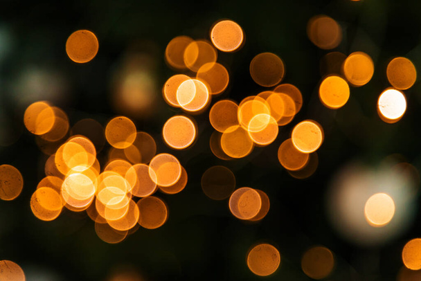 Gelbe Bokeh-Weihnachten auf schwarzem Hintergrund. Selektiver Fokus. Urlaub. - Foto, Bild