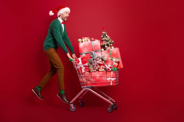 Full size photo of overjoyed excited person jumping pushcart pile stack giftbox isolated on red color background. - Фото, зображення