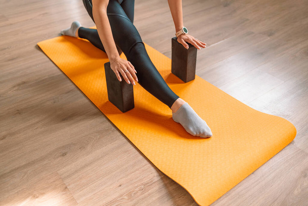 Крупним планом зйомка жіночих рук і ніг, що практикують йогу, використовуючи йогу-блоки для підтримки її тіла
.  - Фото, зображення