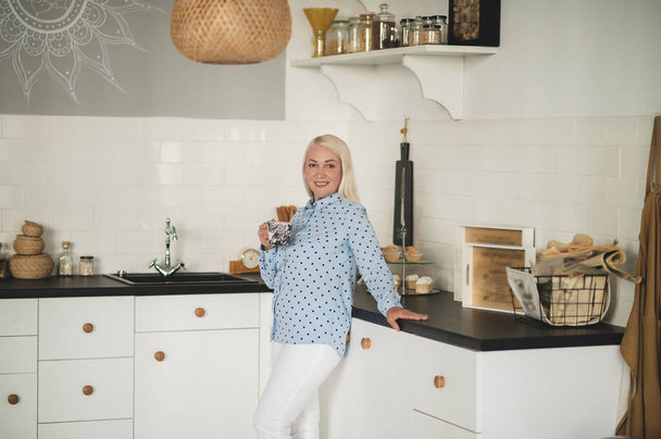 Peaceful morning. Blonde woman having coffee in the kitchen - Photo, image