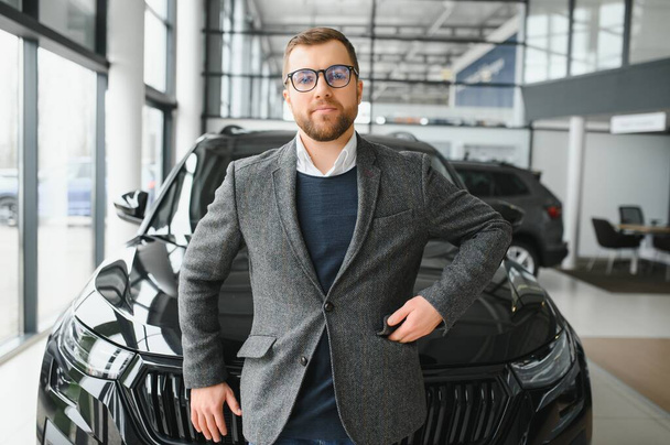 Man minded customer male buyer client in suit choose auto to go look aside want buy new automobile in car showroom - Фото, зображення