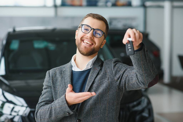 Happy owner of a new car. Emotional handsome man in casual clothes is happy, buying a car in the dealership - Foto, immagini
