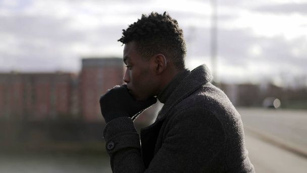 Pensive black African man standing by bridge thinking about life looking at horizon - Foto, Imagem