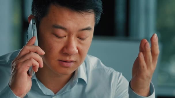 Недовольный мужчина бизнесмен клиент раздражает азиатский корейский сердитый человек говорит мобильный телефон имеет неправильное понимание жалоб проблемы с клиентом решить бизнес-конфликт с помощью смартфона плохой связи сотовой связи - Кадры, видео