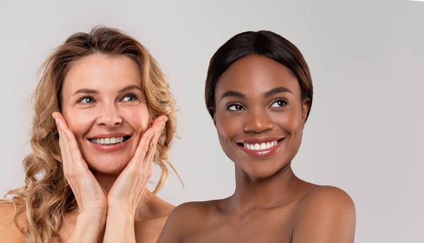 Érett és fiatal szépség koncepció. Boldog középkorú és fiatal fekete nők gyönyörű bőr felett világos szürke háttér, vonzó nők mosolygó és nézi a másolás tér, kollázs - Fotó, kép