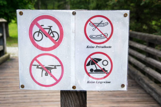 Πινακίδες ποτοαπαγόρευσης σε ξύλινη γέφυρα στην όχθη λίμνης της Αυστρίας. - Φωτογραφία, εικόνα
