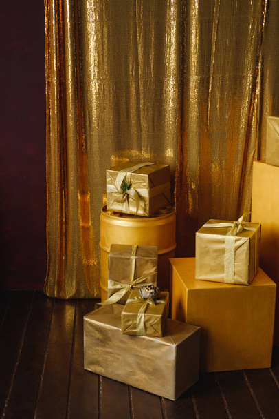 Pilha de presentes coloridos em papel de embrulho dourado com fitas em um fundo dourado brilhante feito de lantejoulas - Foto, Imagem