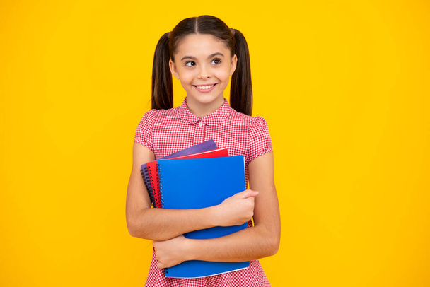 Back to school. Teenager schoolgirl with book ready to learn. School girl children on isolated yellow studio background. Happy teenager, positive and smiling emotions of teen girl - Foto, imagen