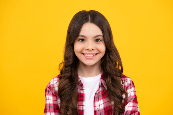 Happy teenager, positive and smiling emotions of teen girl. Close up portrait of caucasian teen girl. Head shot of cute teenager child on yellow isolated studio background - Photo, Image