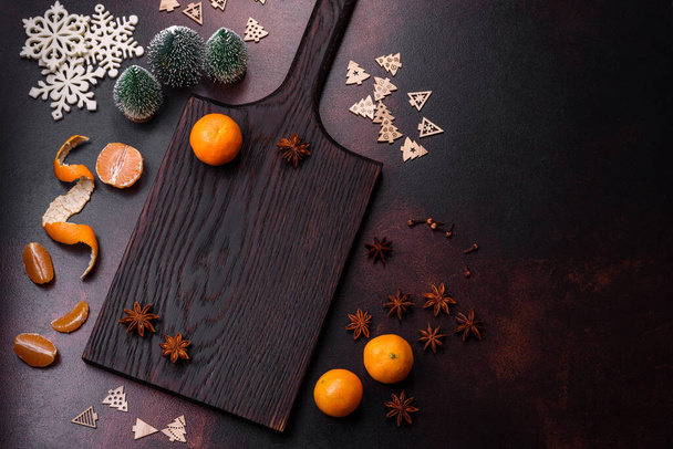 Hermosas decoraciones navideñas con juguetes navideños, clementinas y pan de jengibre sobre un fondo de hormigón oscuro. Preparación de la mesa de Navidad - Foto, imagen