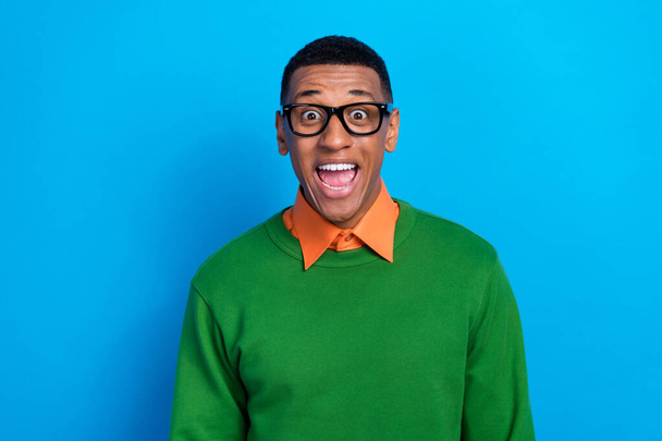 Portrait of carefree positive guy dressed orange shirt under green pullover eyewear open mouth staring isolated on blue color background. - Photo, image