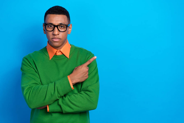 Portrait of serious clever intelligent guy wear orange shirt under green pullover indicating empty space isolated on blue color background. - Zdjęcie, obraz
