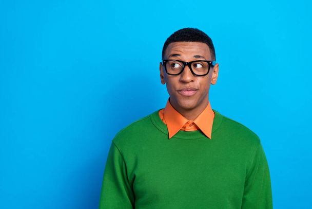 Portrait of intelligent thoughtful guy wear orange shirt under green pullover eyewear look empty space isolated on blue color background. - Fotoğraf, Görsel