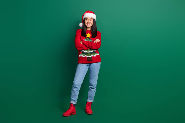 Full length photo of confident funny lady wear red ugly print xmas sweater cap arms folded isolated green color background. - Fotografie, Obrázek