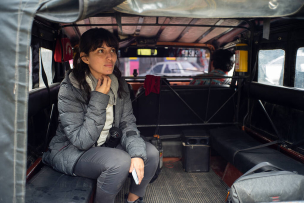 Latin vrouw zitten in de achterbank van een jeep luisteren aandachtig naar haar vriend - Foto, afbeelding