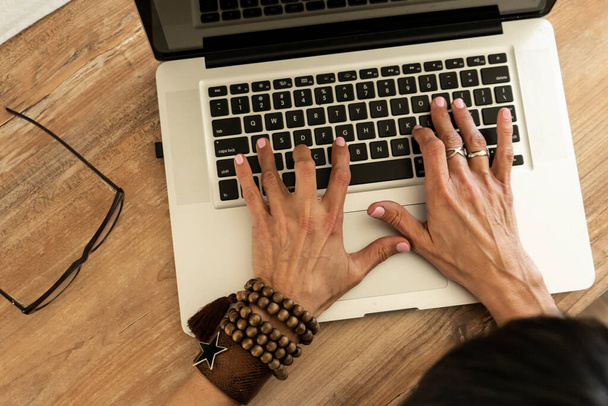 Vista de ángulo alto de las manos de una mujer escribiendo en un teclado portátil. - Foto, imagen