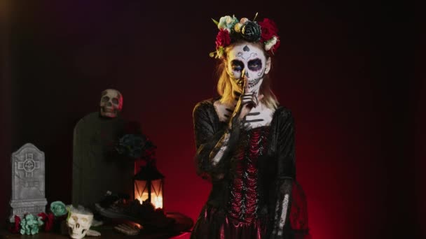 Young scary woman doing hush gesture to keep secret, wearing santa muerte costume and showing slience mute and secrecy sign with finger over lips. Holy dios de los muertos holiday. - Footage, Video