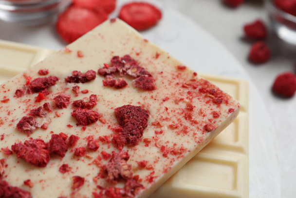 Chocolate bars with freeze dried raspberries on light marble board, closeup - Foto, afbeelding