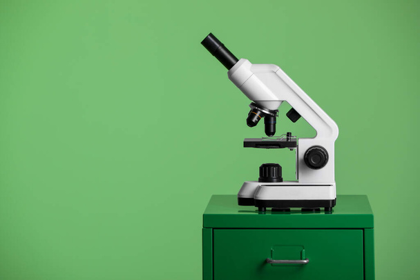 Modern medical microscope on lab drawer against green background, space for text - Fotoğraf, Görsel