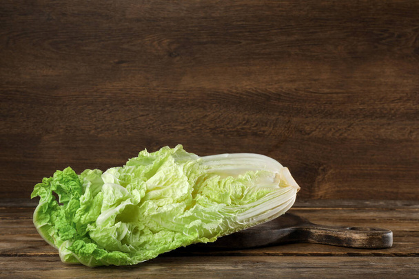Cut fresh ripe Chinese cabbage on table against wooden background - Φωτογραφία, εικόνα