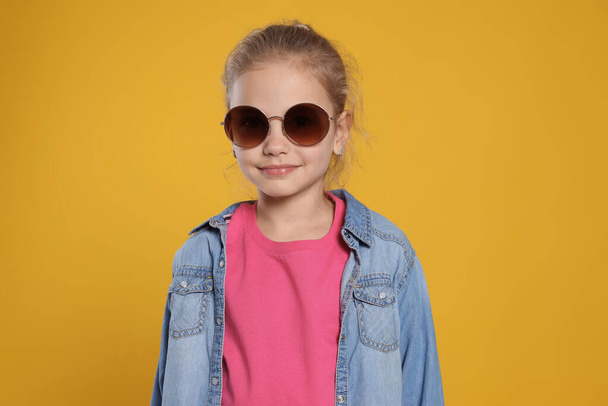 Girl in stylish sunglasses on orange background - Valokuva, kuva