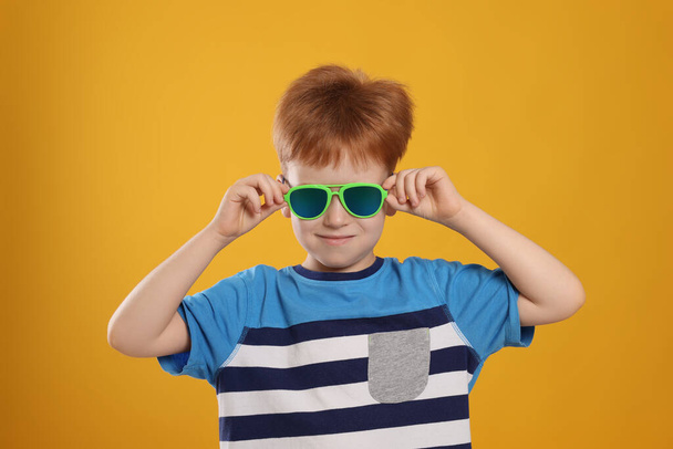 Cute little boy with sunglasses on yellow background - Φωτογραφία, εικόνα