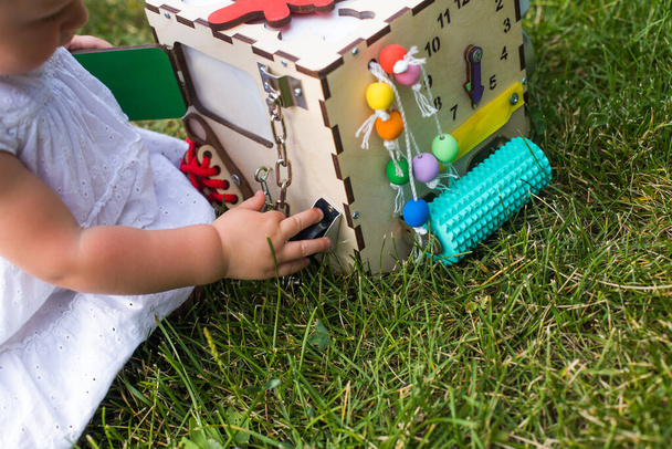 Dítě točí kolečkem na vzdělávací hračce.cube. Šťastné batole holčička si hraje s busyboard kostkou na školce. - Fotografie, Obrázek