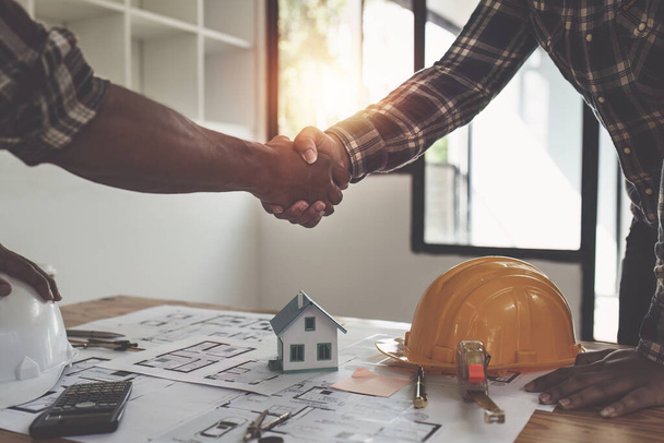 Mimar ve mühendis inşaat işçileri ofis inşaatındaki bir anlaşmayı bitirdikten sonra el sıkışıyorlar, başarı işbirliği konsepti. - Fotoğraf, Görsel