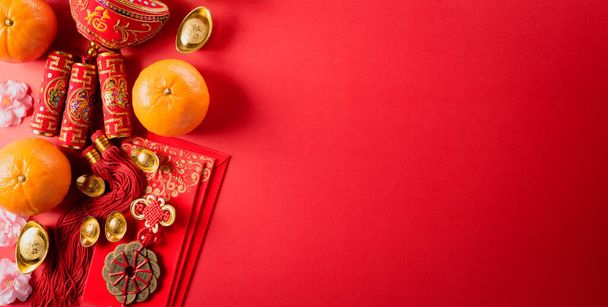 Κινεζική διακόσμηση του νέου έτους από κόκκινο πακέτο, πορτοκαλί και χρυσά πλινθώματα ή χρυσό εξόγκωμα σε κόκκινο φόντο. Κινέζοι χαρακτήρες FU στο άρθρο αναφέρονται στην τύχη καλή τύχη, τον πλούτο, τη ροή του χρήματος. - Φωτογραφία, εικόνα