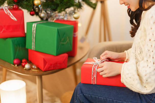 Concetto di Natale, donna asiatica seduta nel soggiorno decorato di Natale e regalo di Natale aperto. - Foto, immagini