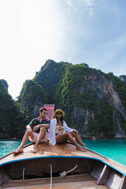 Kilka tajlandzkich kobiet i białych mężczyzn przed łodzią Longtail w lagunie Koh Phi Phi Thailand. Pileh Lagoon Tajlandia Koh Phi Phi - Zdjęcie, obraz