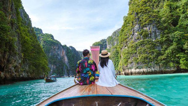 Пара тайских женщин и белых мужчин перед лодкой Longtail в лагуне Ко Пхи Пхи Таиланд. Пилехская лагуна Таиланд Ко Пхи Пхи - Фото, изображение