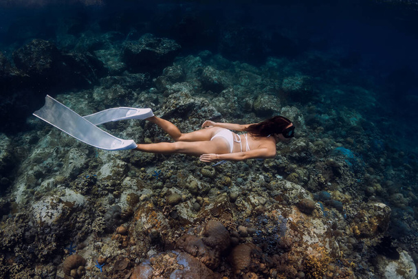 Mujer buceadora libre en bikini blanco con aletas blancas se desliza sobre corales. Libre en el océano tropical - Foto, imagen