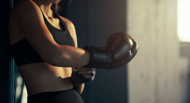 Close-up young woman wearing boxing glove in the gym. - Fotó, kép