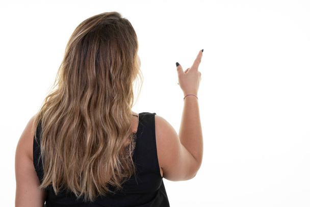 overweight woman standing behind pointing to side object on copy space rear view - Photo, Image