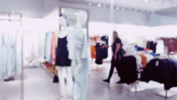 Moda, comercio minorista y tienda, visión interior borrosa de la tienda de ropa de ropa en el centro comercial de lujo como fondo desenfocado. Imágenes de alta calidad 4k - Metraje, vídeo