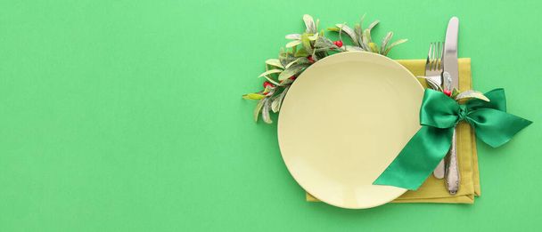 Beautiful Christmas table setting with mistletoe on green background with space for text - Фото, изображение