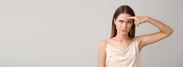 Portrait of young displeased woman with acne problem on light background with space for text - Photo, Image