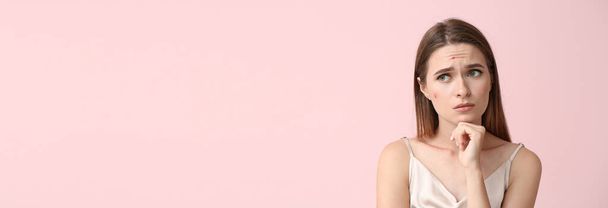 Portret van trieste jonge vrouw met acne probleem op roze achtergrond met ruimte voor tekst - Foto, afbeelding