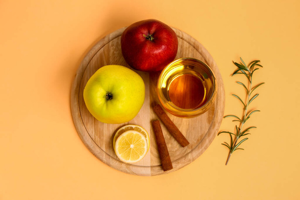 Houten bord met verse appels, glas sap en kaneelstokjes op kleurenachtergrond - Foto, afbeelding