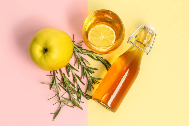 Розмарин, бутылка и стакан свежего яблочного сока на цветном фоне - Фото, изображение